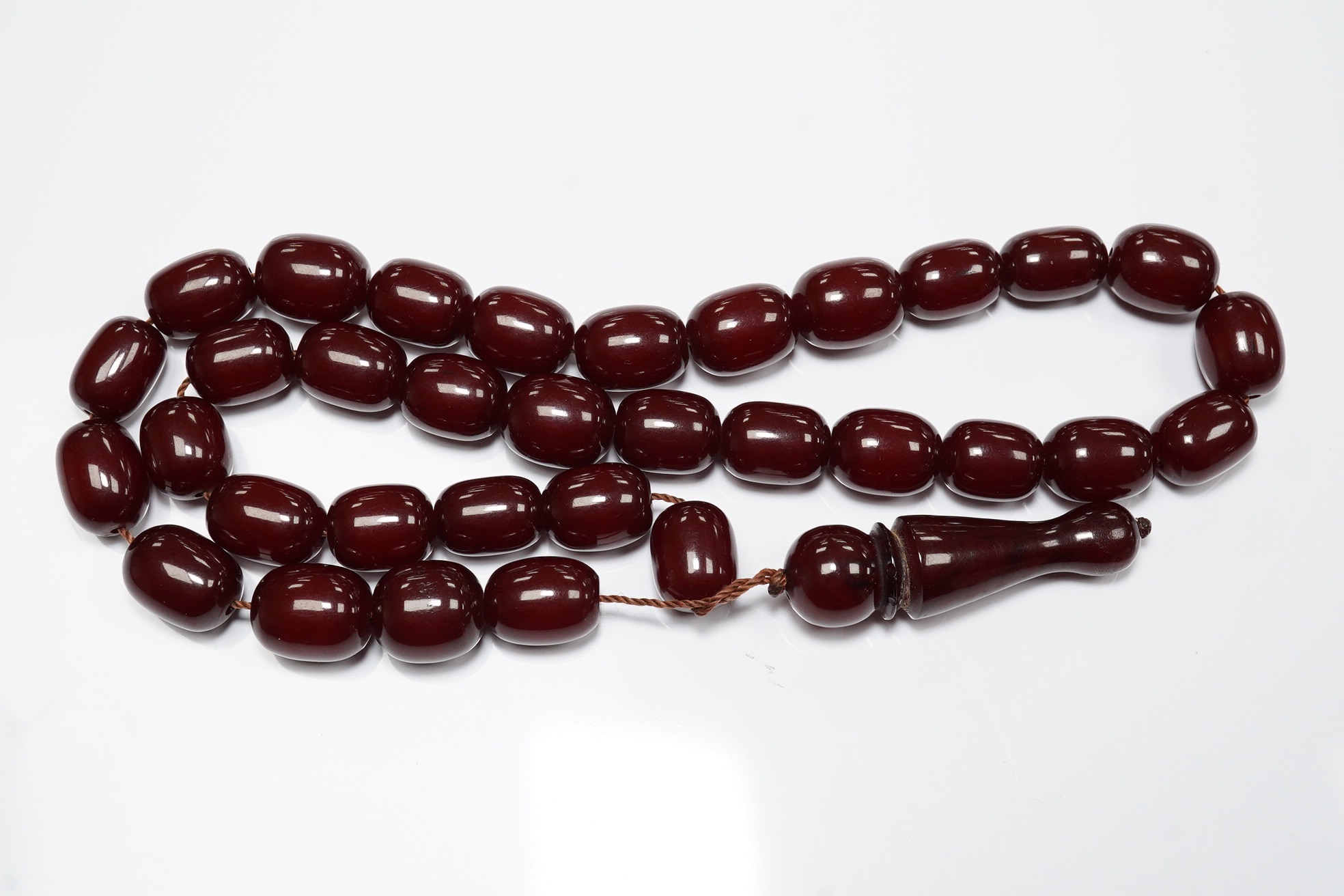 A Persian single strand simulated cherry amber drop bead necklace, 64cm, gross weight 54 grams. Condition - fair to good